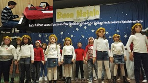 Luca Iuliano suona il piano mentre i bambini della 4C della scuola primaria del Galluppi recitano i brani Natalizi e cantano copia