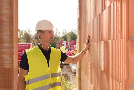 Builder touching bare brick wall