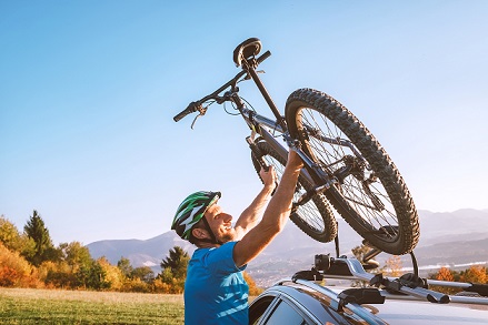 Mountain biker man take of his bike fronm the car roof. Active sport people concept image